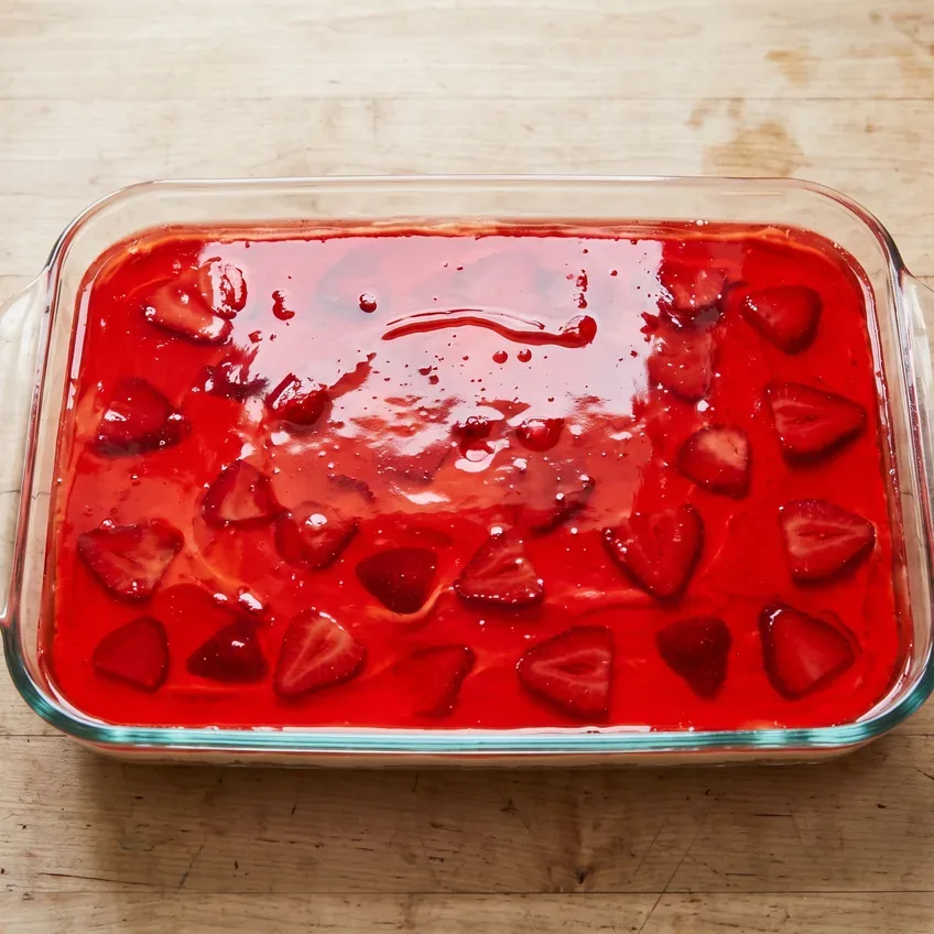 The gelatin layer just poured over the cream layer and spread level, the strawberry slices suspended through it rather than floating on top.