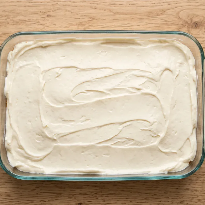 The pale cream cheese layer spread over the cooled crust, taken right into the corners and sealed against all four sides of the dish.